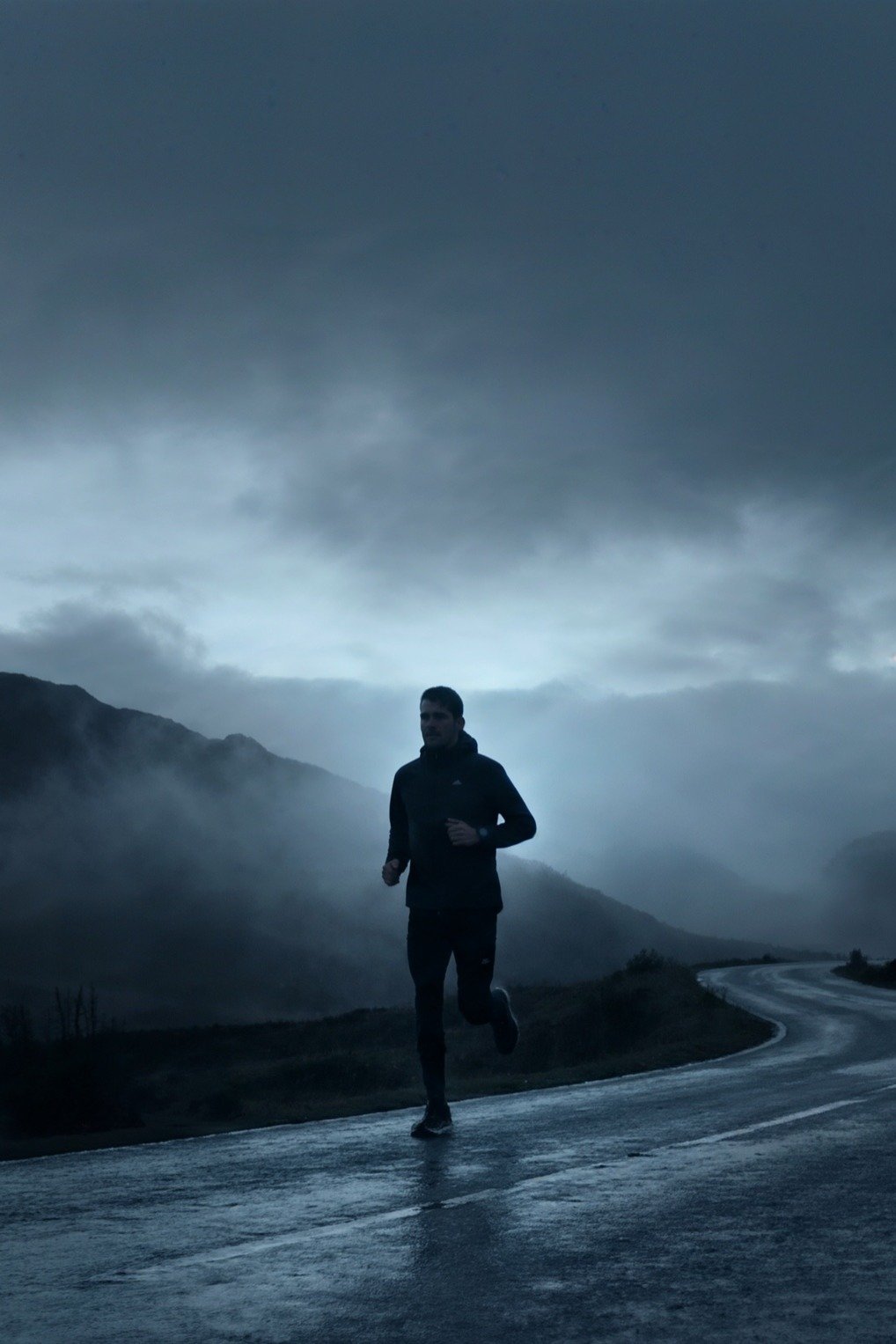 A runner on a misty mountain road at dawn